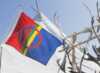 Sami flag with lavvo in background and reindeer antlers.